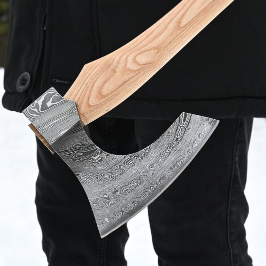 Person holding a decorative axe with a detailed blade against a neutral background