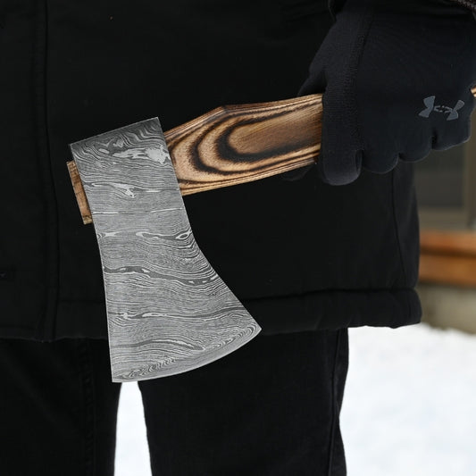 Person holding a decorative axe with a wooden handle and metal blade, wearing a black jacket and gloves.