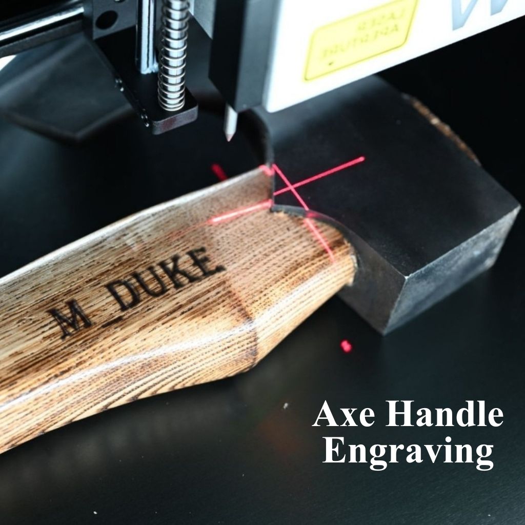 Wooden axe handle being engraved with 'M. DUKE' using a laser engraving machine.