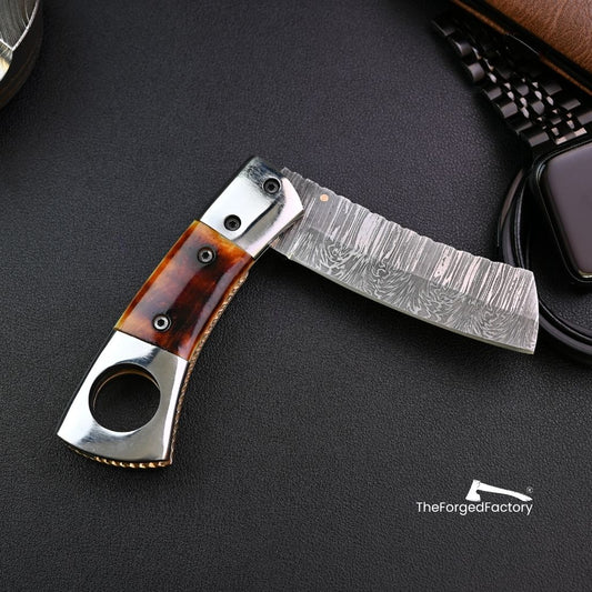 Foldable ciga knife with bone handle on a dark surface, brand 'The Forged Factory' visible