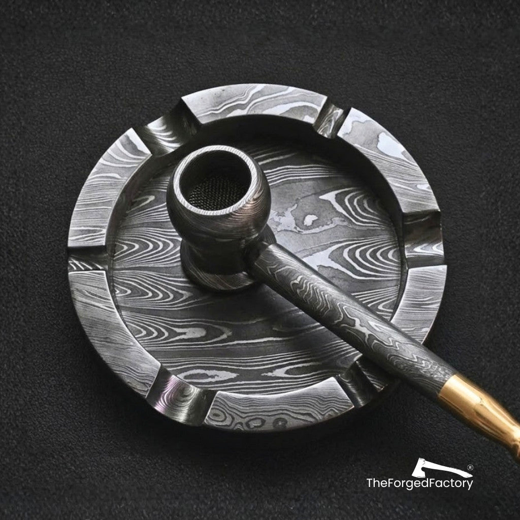 Damascus steel pipe and large ashtray set on a black background with 'The Forged Factory' branding.