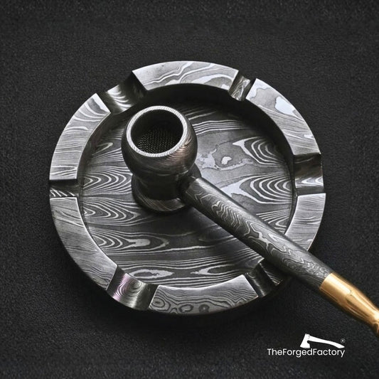 Damascus steel pipe and large ashtray set on a black background with 'The Forged Factory' branding.