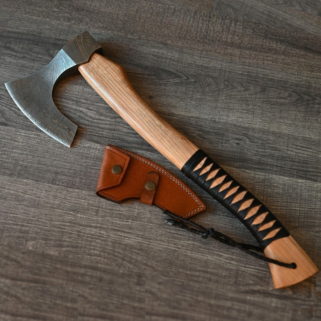 handmade ash wood handled splitting axe with leather sheath on a wooden surface