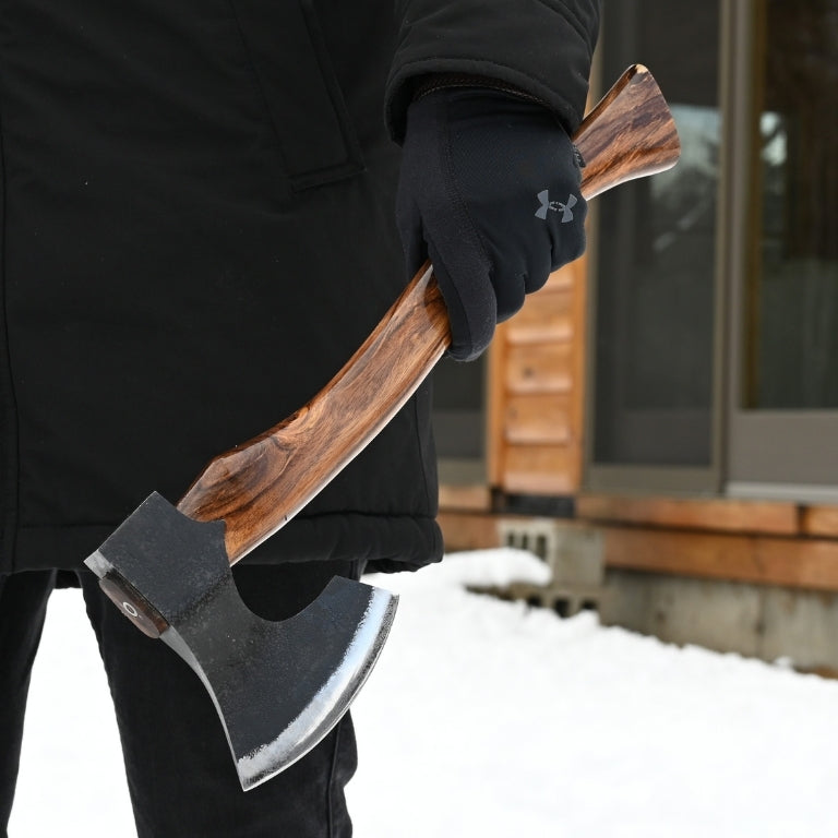Person holding a splitting axe with a wooden handle outdoors in winter