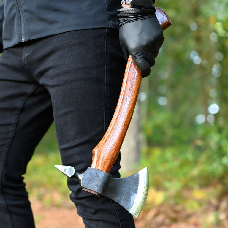 Person holding a axe with a wooden handle in a forest setting