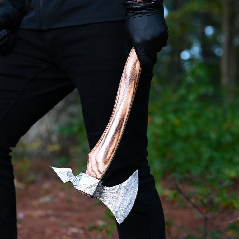 Person holding a large hand forged axe in a forest setting