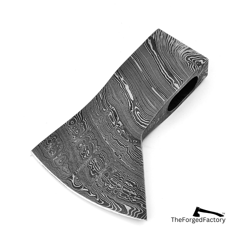 Decorative axe head with a unique pattern on a white background, branded 'The Forged Factory'.