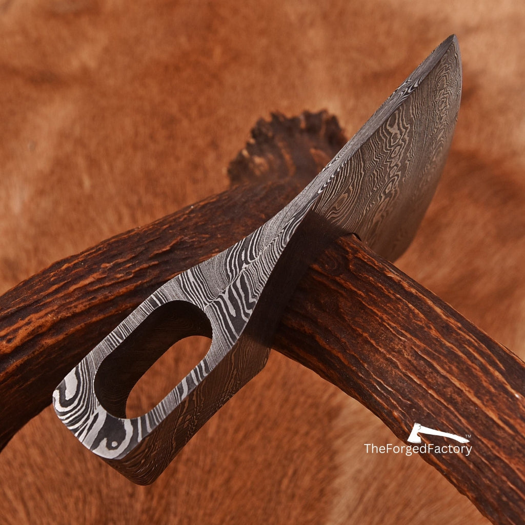 Hand-forged knife with Damascus steel blade and wooden handle on a wooden background, branded 'The Forged Factory'.