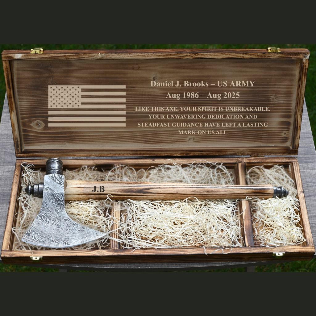 Wooden box with engraved American flag and text, containing a Functional outdoor bushcraft axe.