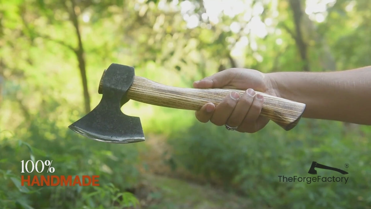 Multi-angle outdoor video of handmade bushcraft hatchet with wooden handle, showcasing forged axe craftsmanship in a forest setting.